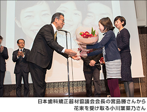 日本歯科矯正器材協議会会長の宮島勝さんから花束を受け取る小川葉菜乃さん